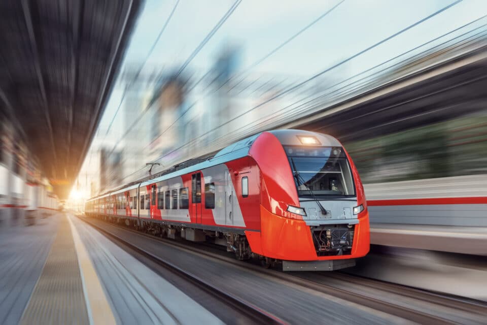 roter Zug fährt durch Bahnhof im Sonnenuntergang